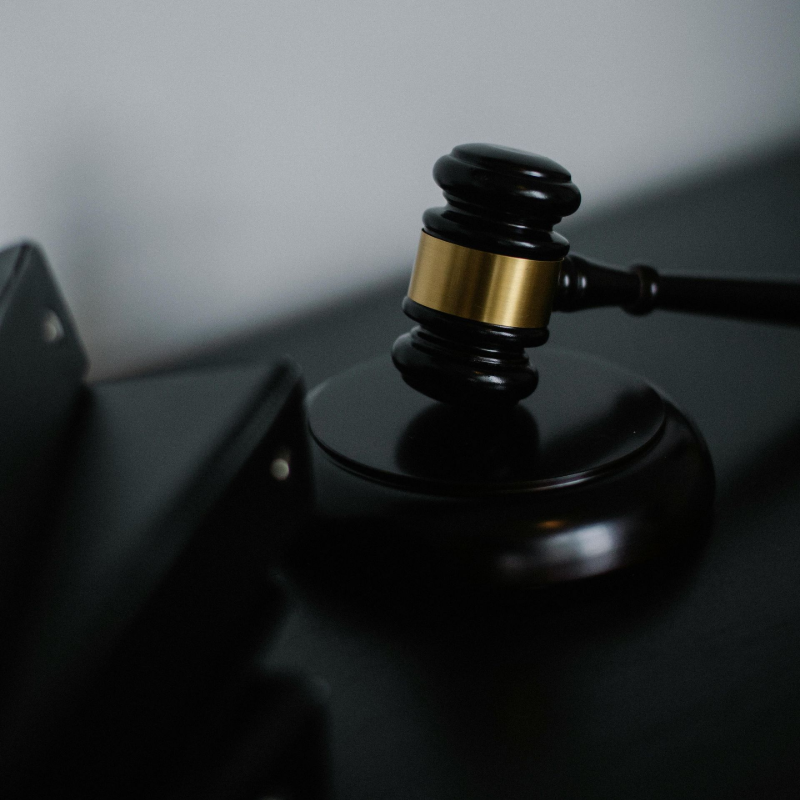 A gavel resting on a sound block beside dark case folders